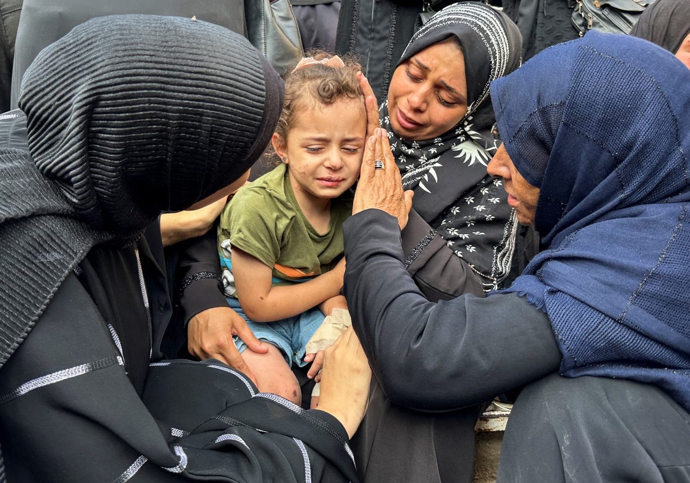 A Palestinian child surrounded by grieving family members